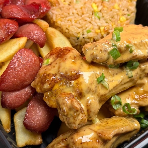 Chicken wings with creamy sauce, french fries, sliced sausage, and fried rice.